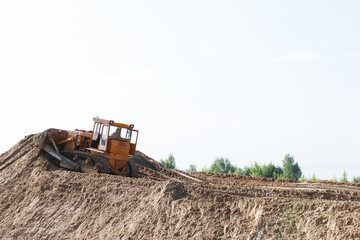 Bulldozer climbs a dirt hill at a construction site in a rural area. The scene captures heavy...