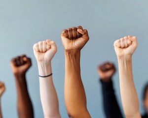 Raised fists of diverse skin tones symbolizing unity, strength, and solidarity against a neutral background.