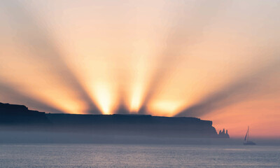 Sun Rays Over Misty Coastal Cliffs