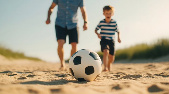 A child and an adult play soccer barefoot on a sandy path under clear skies, enjoying a sunny day outdoors.