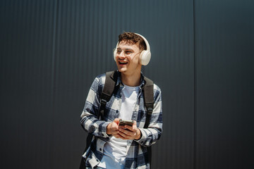 Portrait of a young adult man student smile with wireless headphones on black wall background