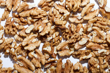 Close-up of raw walnut kernels spread out on a white surface. Healthy and natural snack concept. Great for illustrating organic food, nutrition, plant-based diets, or ingredient-based themes.

