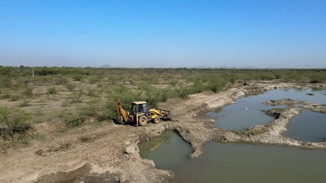 Top View of Backhoe Loader Operating on Dirt Road in Indian Village