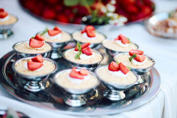 Mini strawberry cheesecakes served in elegant metal cups topped with fresh strawberries and mint...