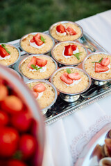 Mini strawberry shortcakes with whipped cream and mint leaves, arranged on a silver tray atop a...