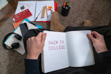 Student hands holding an open notebook with school supplies scattered around