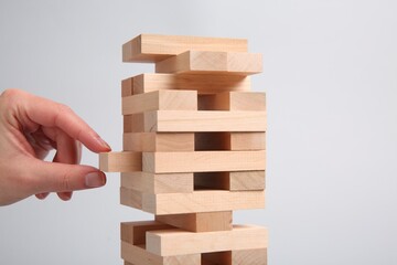 Lviv, Ukraine - December 04, 2023: Woman playing Jenga on light gray background, closeup