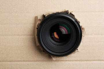 Hidden camera lens through hole in cardboard, closeup