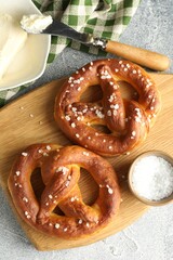 Tasty pretzels with salt and butter on light grey table, flat lay