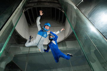 A male instructor teaches a woman how to fly in a wind tunnel. Free fall simulator.