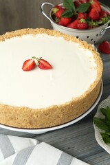 One tasty cheesecake, strawberries and mint on grey wooden table, closeup
