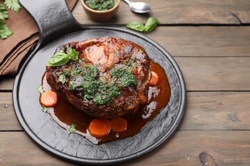 Traditional ossobuco dish with beef steak and sauce served on wooden table, above view. Space for text