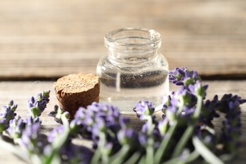 Natural essential oil and lavender flowers on wooden table, closeup