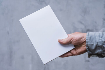 Realistic mockup of book cover, magazine in the hands of a man on concrete background. Concept for...