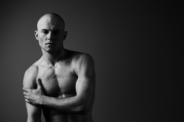 Black and white portrait of a man with a serious expression, showcasing defined muscles and strong...