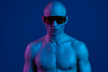 Athletic man wearing sunglasses on a blue background, showcasing a striking blue tone. The image...