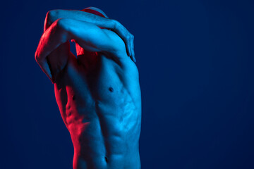 Muscular man posing in dynamic motion, showcasing strong physique with dramatic lighting, blue and red colors enhance the visual impact.