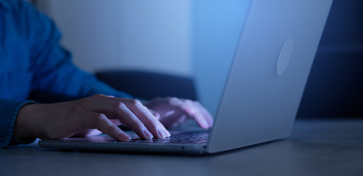 close up developer man hand type keyboard input code for register system software or unlock password on laptop in dark operation office room for cyber security technology and work from home concept