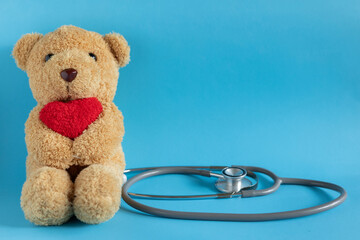 close up teddy bear with heart as paediatrician with stethoscope and heart on blue color background...