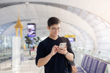 close up young asian man smile and looking while holding passport ,ticket and smartphone in airport departure area for traveling and people lifestyle concept