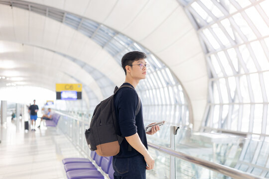 close up young asian man look while holding passport ,ticket and smartphone in airport departure area for traveling and people lifestyle concept