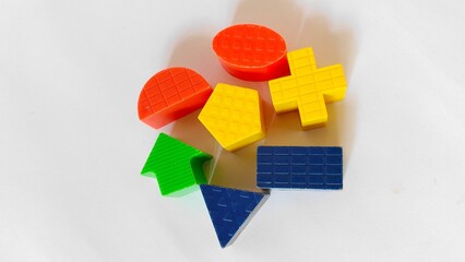 Colorful plastic geometric shapes used for educational or learning activities, placed on a white...