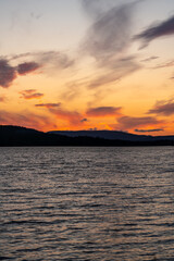 Vibrant sunset colors reflect on Hällsjön lake, surrounded by the stunning Långfjället Nature Reserve in Sweden, offering a serene and picturesque view