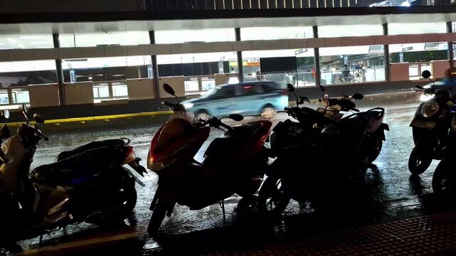 Nighttime highway activity with vehicles going back and forth on rainy days. Cars, motorcycles in rainy and night urban condition.
