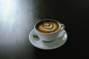 Close-up shot of a creamy latte in a white ceramic mug, evoking the warmth, comfort, relaxation and quiet enjoyment of a quiet and mindful coffee break.
