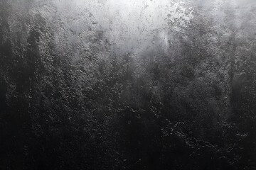 Obraz premium A textured black stone surface, conveying a sense of depth and raw beauty. The surface of the stone has rough, irregular patterns and textures