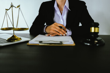 Lawyers sit at a table with legal documents, hammers and scales in the service of justice,...