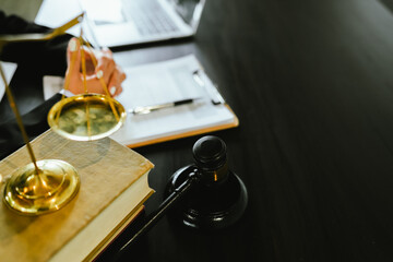 Lawyers sit at a table with legal documents, hammers and scales in the service of justice,...