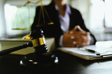 Lawyers sit at a table with legal documents, hammers and scales in the service of justice, representing law, authority, consultation, legal process and decision-making in court.