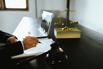 A gavel rests on a legal desk with blurred background of a professional signing documents,...