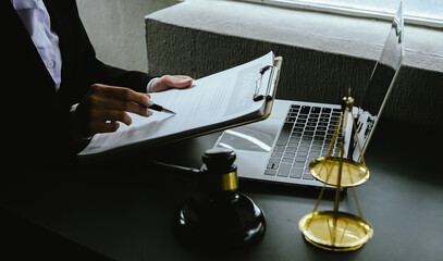 A gavel rests on a legal desk with blurred background of a professional signing documents,...