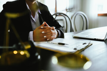 Lawyers sit at a table with legal documents, hammers and scales in the service of justice, representing law, authority, consultation, legal process and decision-making in court.