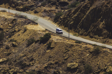 A white van is driving down a curvy road in a desert