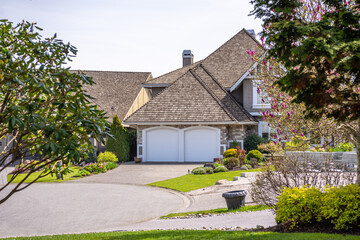 Garage door in luxury house with trees and nice landscape in Spring in Vancouver, Canada, North America. Day time on May 2025.