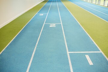 Blue track lanes are extending into perspective in flat design with green turf, white wall, windows