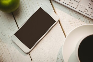 White smartphone is lying on wooden table in flat design with keyboard, coffee mug, green apple © vectorfusionart