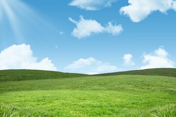 Rolling grassy hills are being shown in flat design with scattered white clouds and sun rays