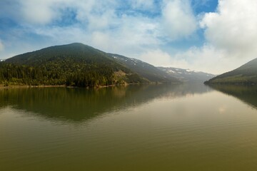 Mountain range reflecting on river against sky