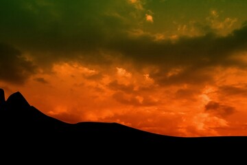 Obraz premium Flat design illustration showing dark dune silhouette under vibrant orange and green sunset clouds