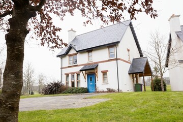Obraz premium Detached two-story house is resting in flat design, showing blue door, curved driveway, green lawn