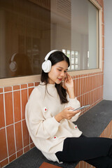 Asian woman wearing headphone listen to music and using smartphone choose playlist