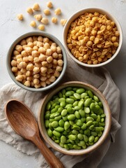 Fototapeta premium Assorted legumes: chickpeas, roasted lentils, and edamame in bowls with wooden spoon.