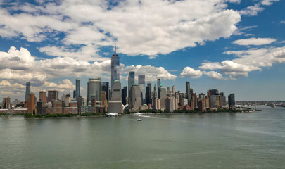 Fototapeta premium Manhattan aerial skyline, New York. Panorama view of New York city skyscrapers on blue sky. USA NYC. Lower NYC skyline on sunny day. New York cityscape. New York City with clouds from drone.
