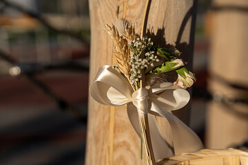 A charming wedding decoration features dried flowers tied with a ribbon on a wooden post. The...