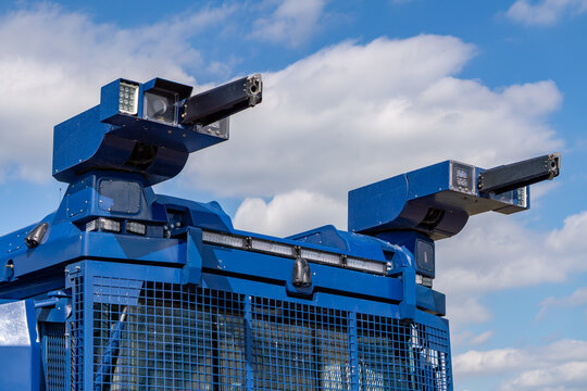 Riot control vehicle turret with water cannons and spotlights mounted on armored police truck against blue sky