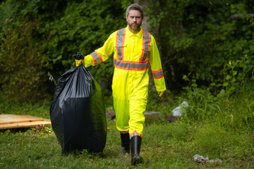 Volunteer man collecting garbage, picking up waste at nature. Land pollution, environmental...